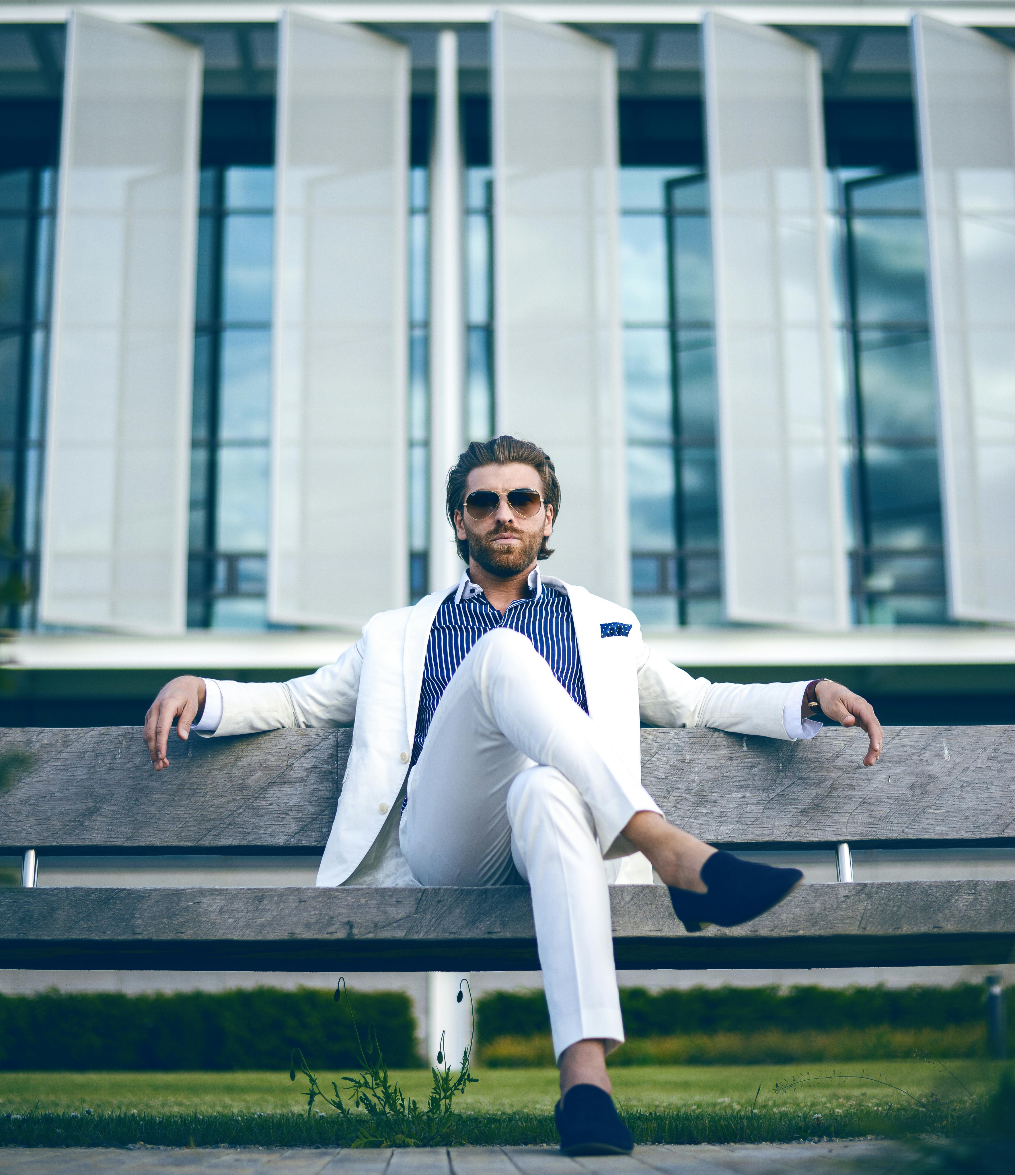 Stylish man sitting on a bench using a laptop