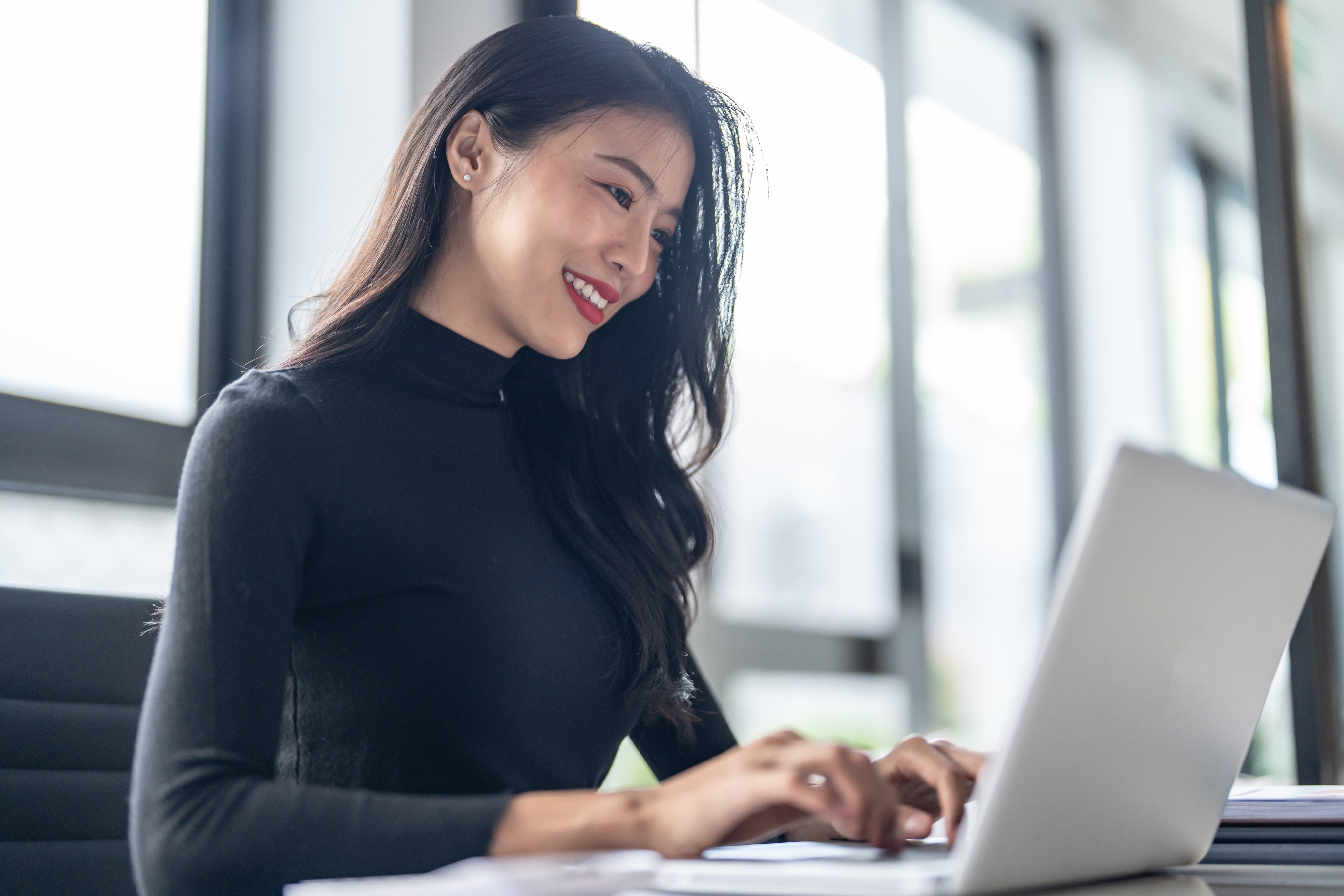 Woman smiling while working on a laptop
