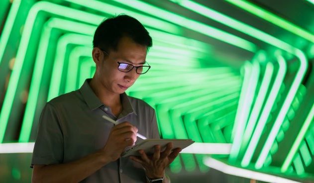 Man using a tablet in a room with green neon lights