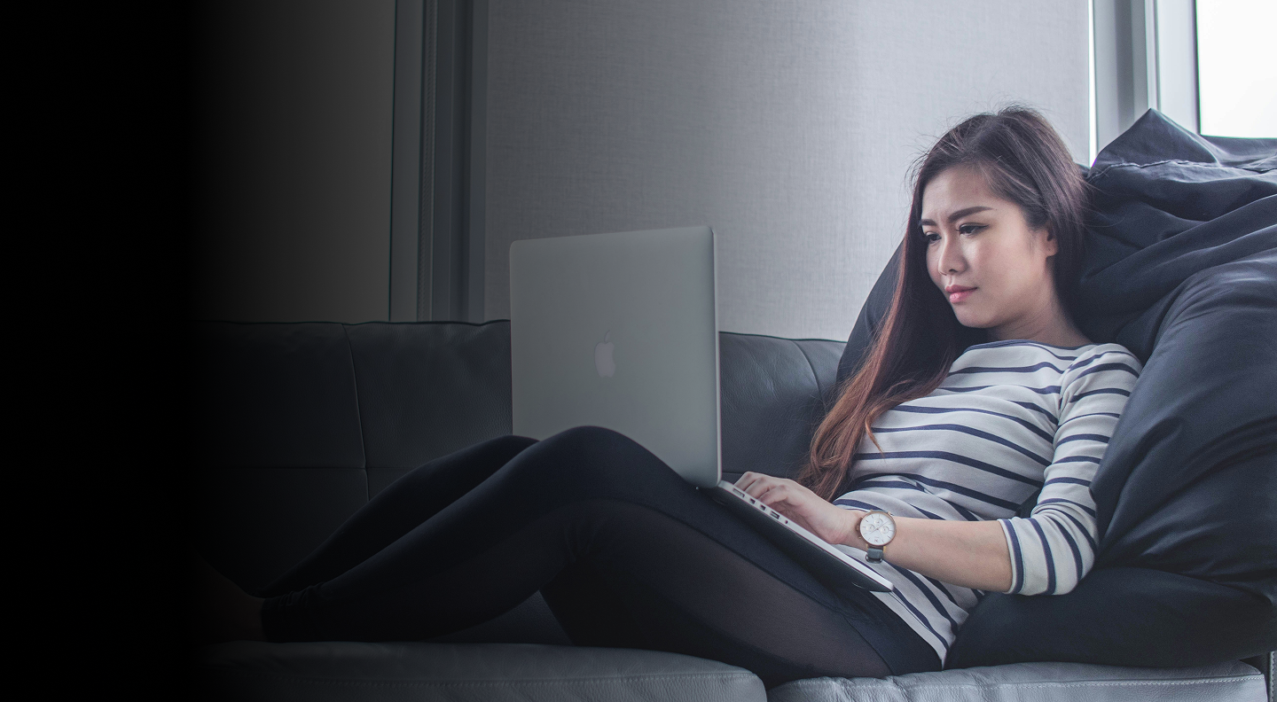 Woman coding on a laptop while sitting on a couch